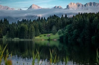 Paisaje montañoso sereno con reflejos y una cabaña rústica