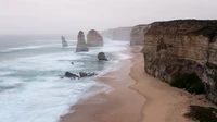 Falésias majestosas encontram o mar tranquilo ao pôr do sol, exibindo formações rochosas imponentes ao longo de uma costa serena.