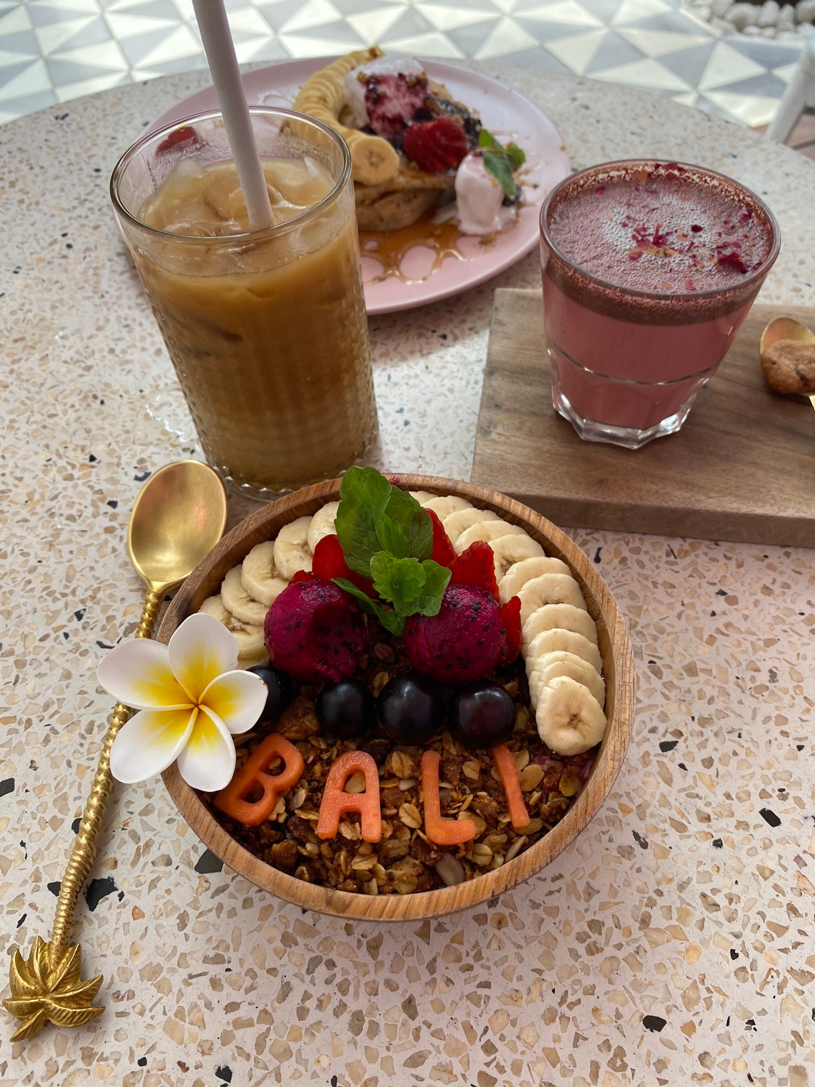 There is a bowl of fruit and a drink on a table (drink, smoothie, panna cotta, frozen dessert, food)