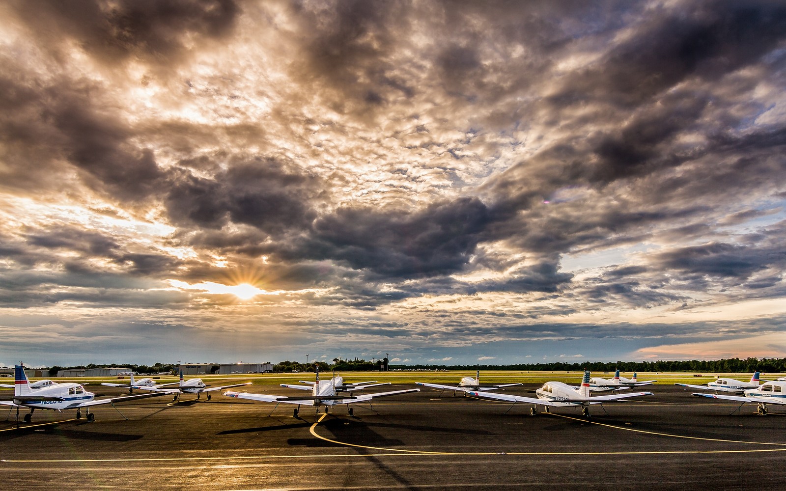 Nuages arabes au-dessus d'une piste avec plusieurs petits avions garés (nuage, horizon, mer, ciel, voyage aérien)