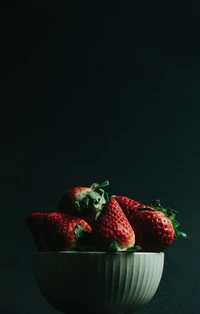 Fresas frescas en un tazón gris contra un fondo oscuro