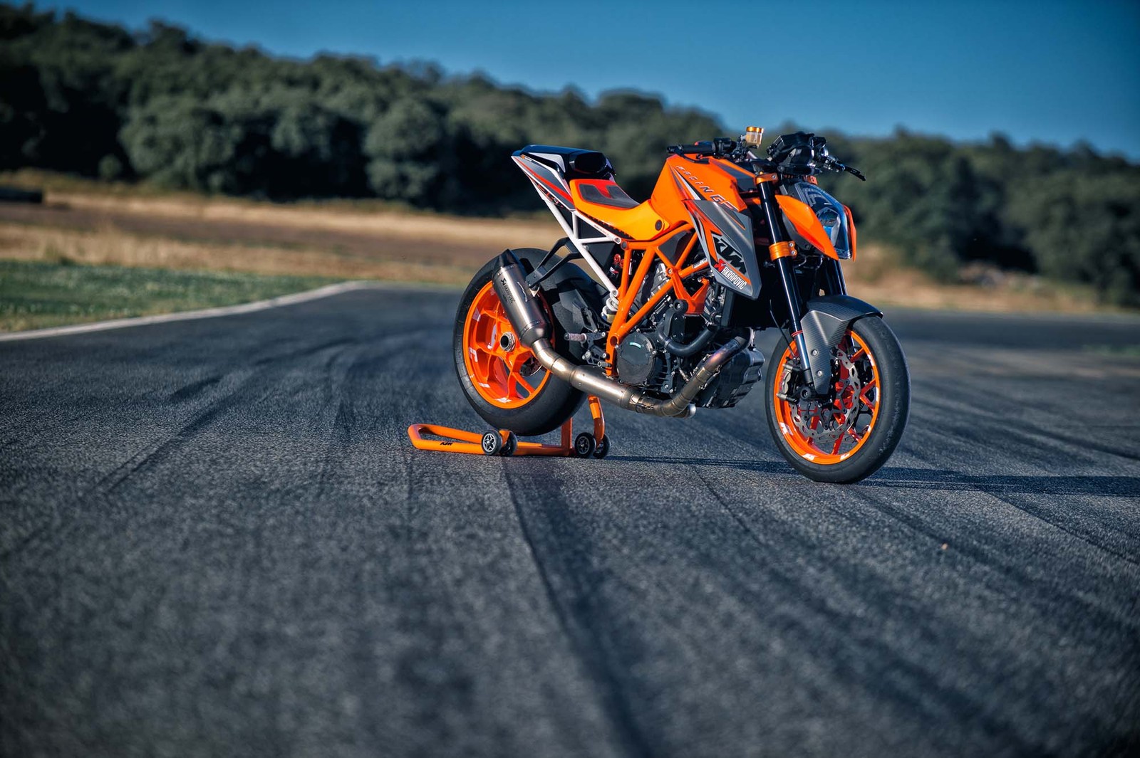 Motocicleta árabe en una carretera con ruedas naranjas y cielo azul (ktm, motocicleta, supermoto, motociclismo, deportes de motor)