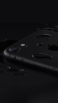 Black iPhone 7 with droplets on a sleek surface.