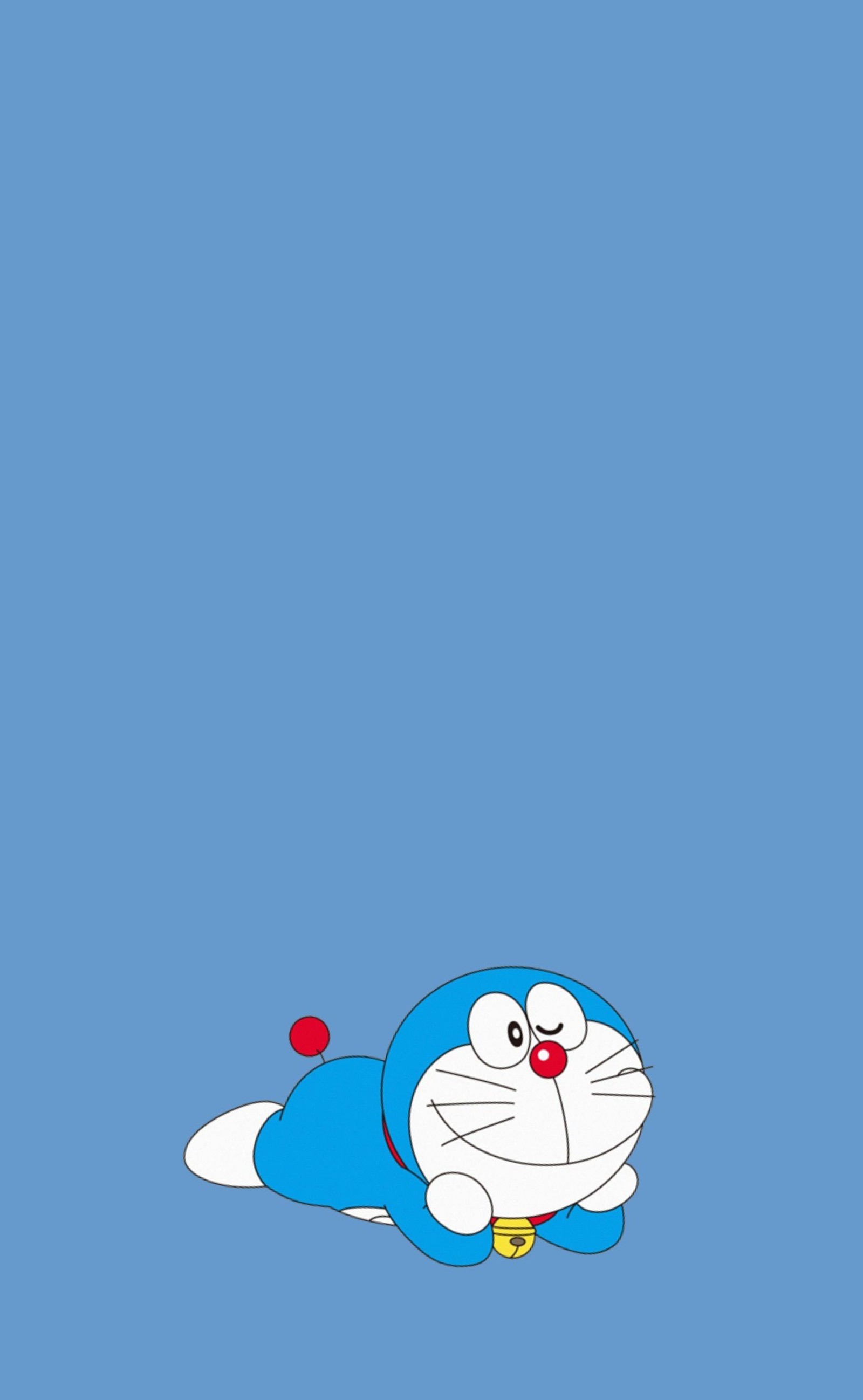 Un primer plano de un personaje de dibujos animados acostado sobre una superficie azul (increíble, azul, blue cat, cat, doraemon)