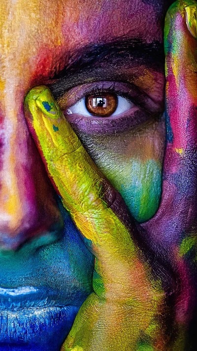 Œil vibrant avec peinture colorée sur les mains et le visage