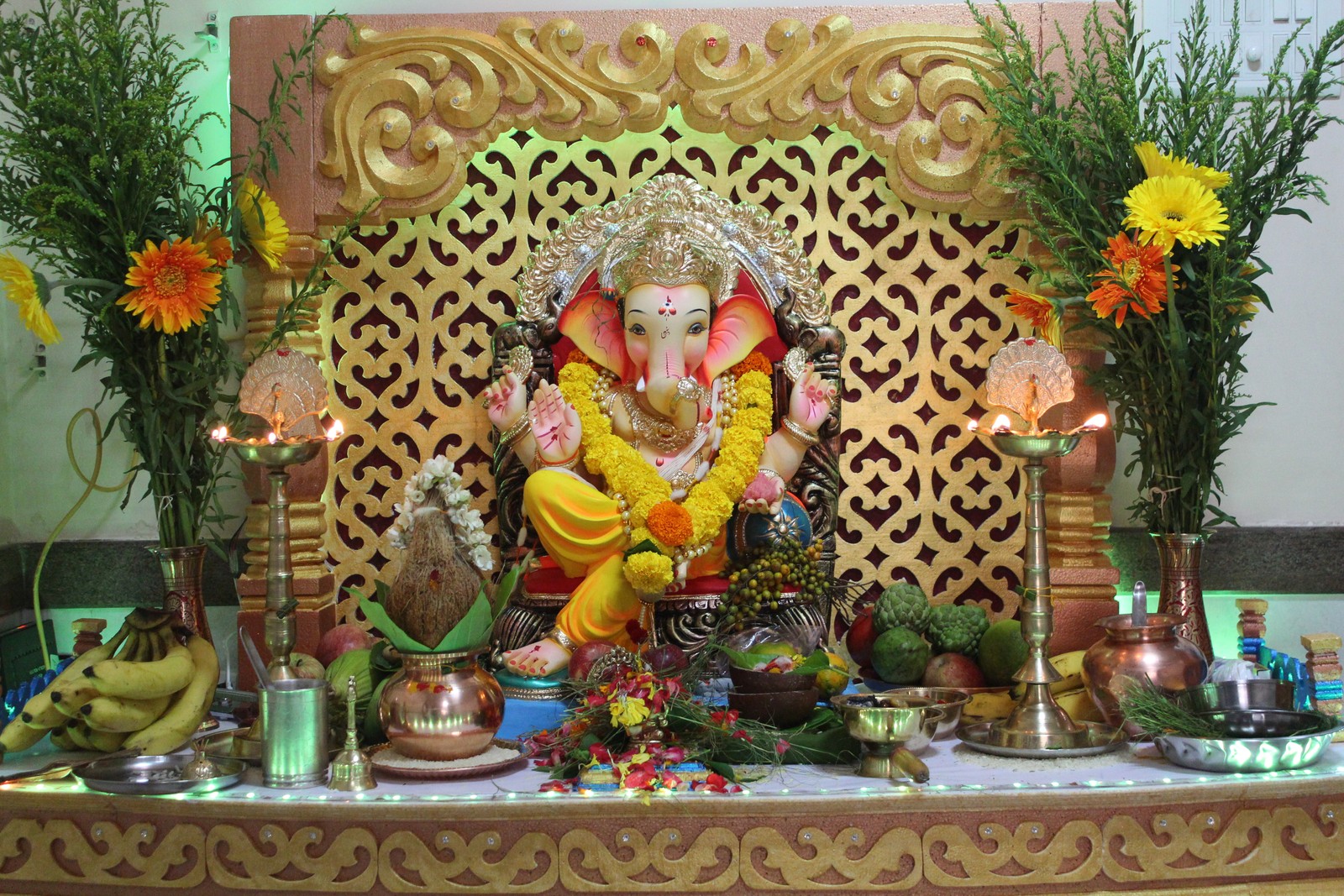 Hay una estatua de ganesha en una mesa con flores. (ganesh, imagen)