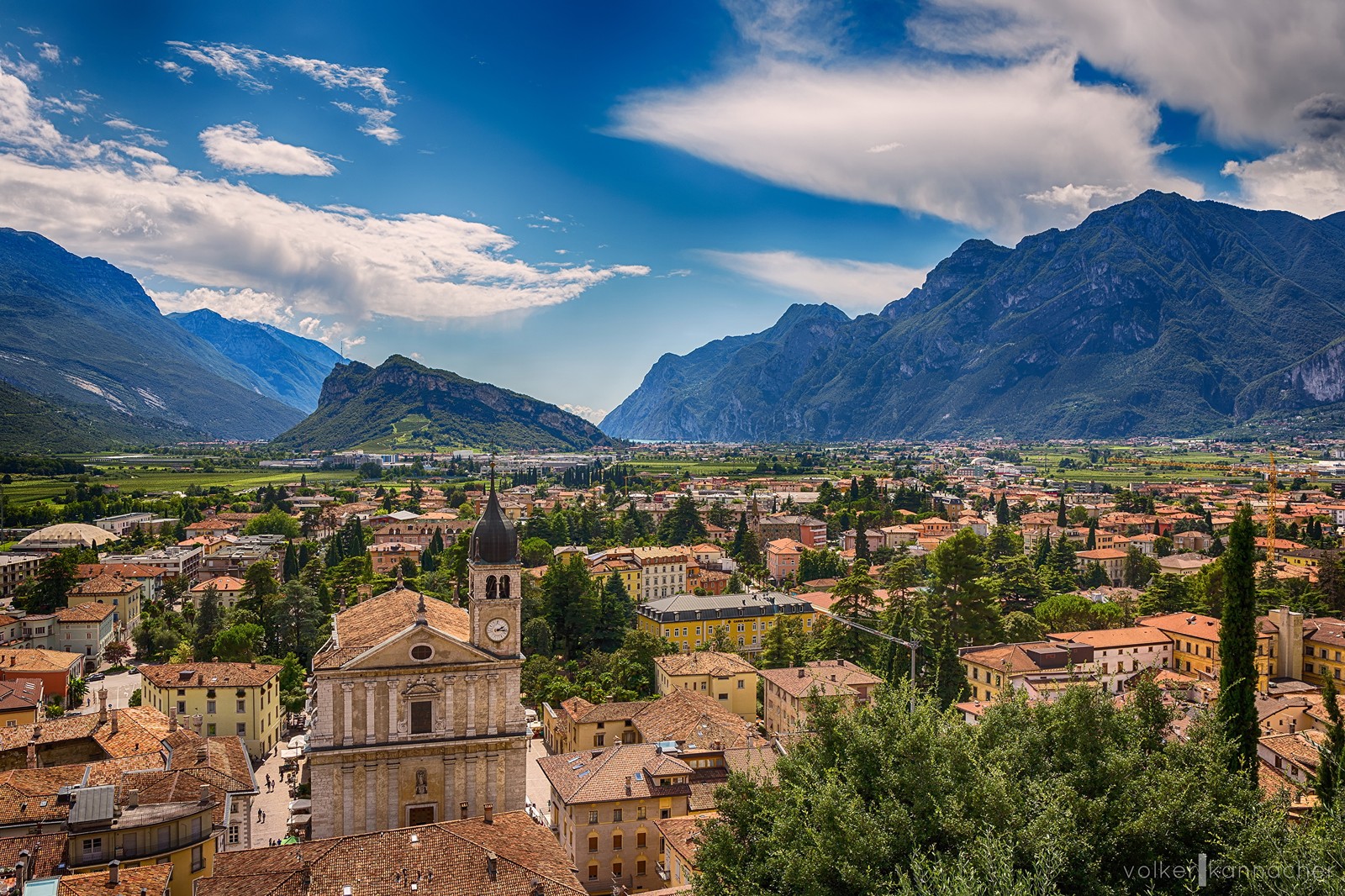 Uma vista de uma cidade com montanhas ao fundo (lago de garda, cidade, formas montanhosas, montanha, aldeia montanhosa)