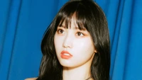 Momo von TWICE mit auffälligem Blick vor blauem Hintergrund