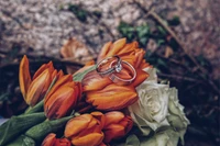 Elegante Hochzeitsringe, die auf einem lebhaften Bouquet aus orangefarbenen und gelben Tulpen ruhen