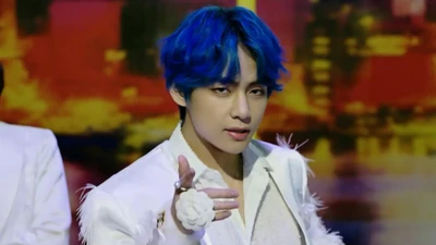 V do BTS com cabelo azul marcante, vestido com um traje branco, cativando o público com uma pose carismática.