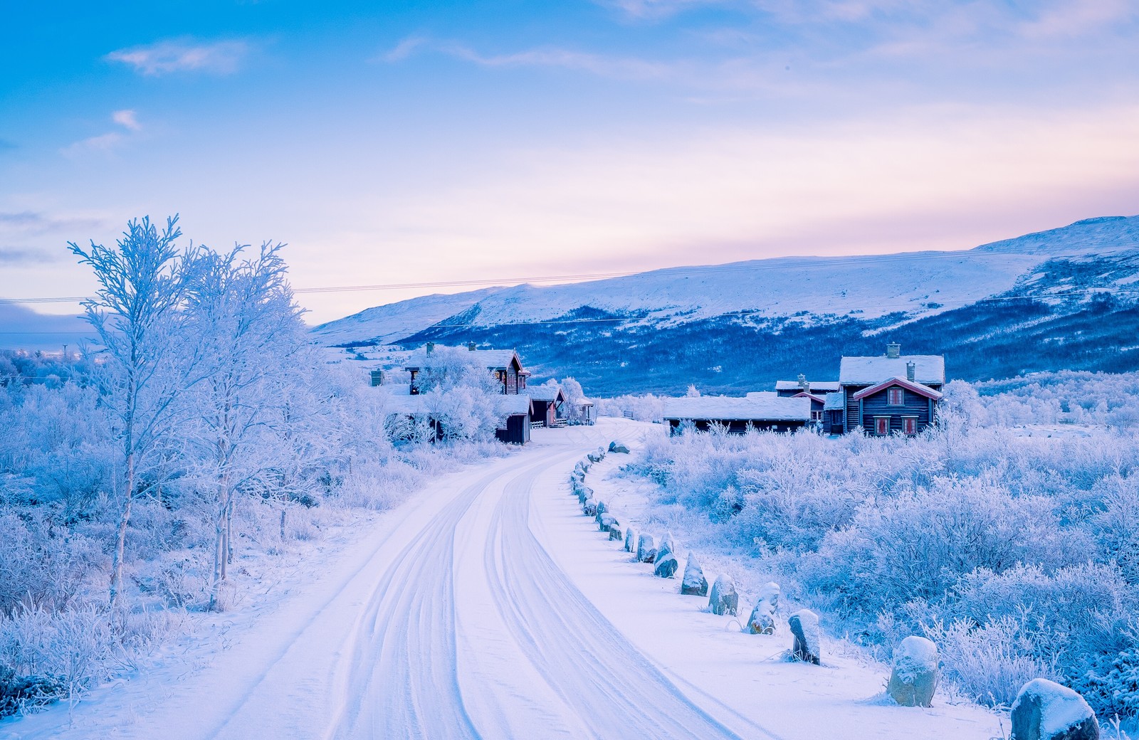 Estrada coberta de neve com uma casa e uma montanha ao fundo (estrada de neve, neve, inverno, congelamento, estrada)