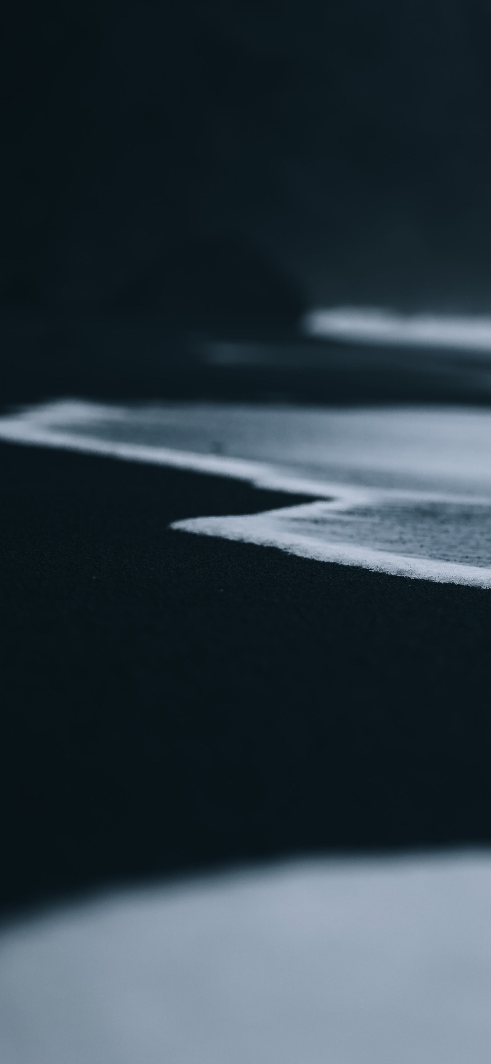 There is a small bird standing on the beach near the water (reflection, earth, atmosphere of earth, water, automotive tire)