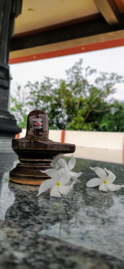 Shivling com flores brancas em um ambiente sereno de templo