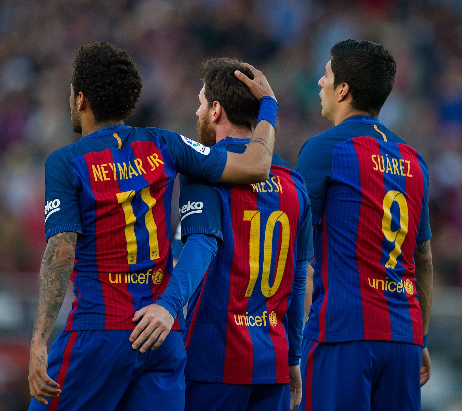 Jogadores de futebol arrafed em uniformes azuis e vermelhos se congratulam (barca, messi, msn, neymar, suárez)