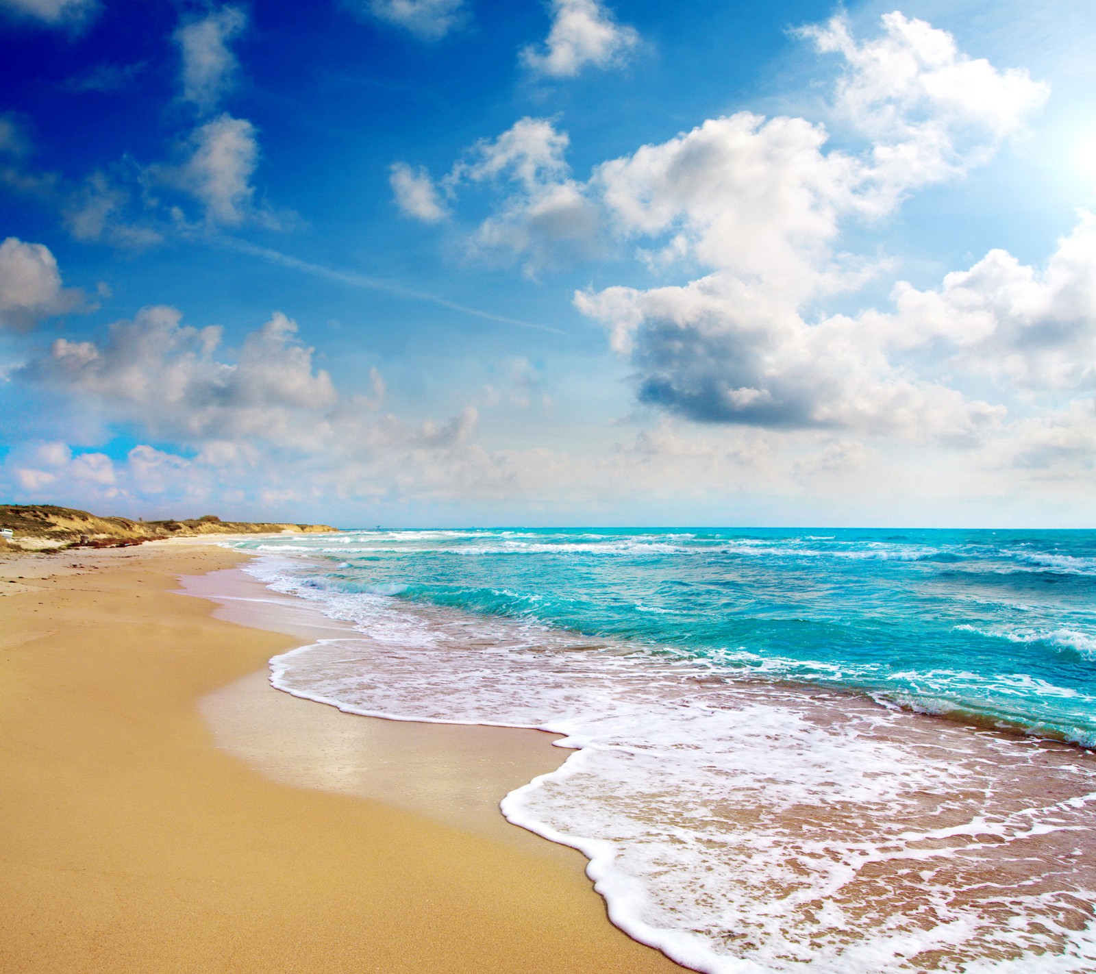 Uma praia com ondas e céu azul com nuvens. (praia, natureza, mar, costa, céu)