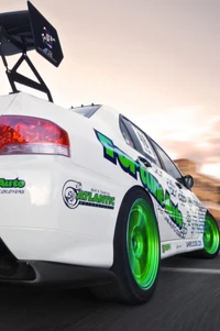 Sporty white car with vibrant green wheels and an oversized rear wing, captured in motion.