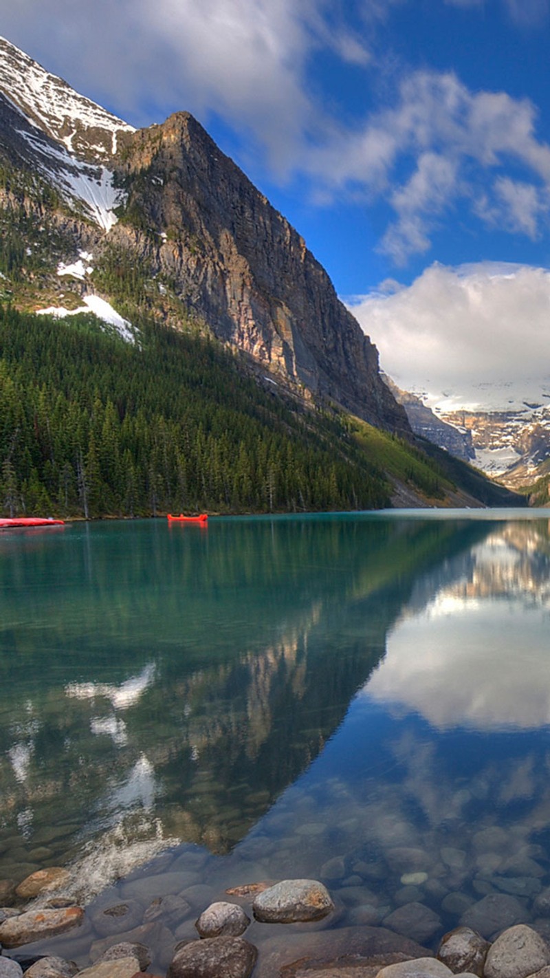 There is a boat that is sitting on the water in the mountains (android, iphone, lake, mountain, natural)