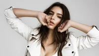 Emily Ratajkowski con una elegante chaqueta blanca, adoptando una pose segura.