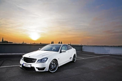 Sleek Mercedes-Benz E-Class Coupe with custom alloy wheels, parked against a stunning sunset backdrop.