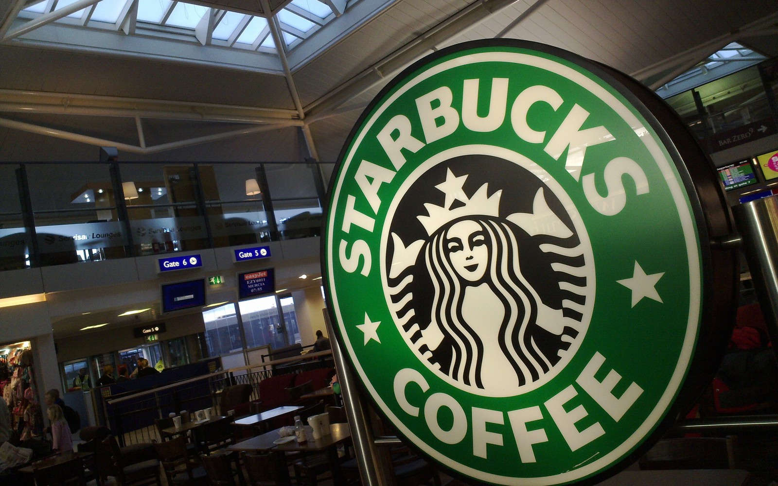 Sinal do starbucks em um shopping com pessoas passando (starbucks, café, sinalização)