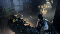 Lara Croft observe discrètement son environnement perchée sur une branche d'arbre dans une jungle dense, prête à affronter des ennemis dans "Shadow of the Tomb Raider".