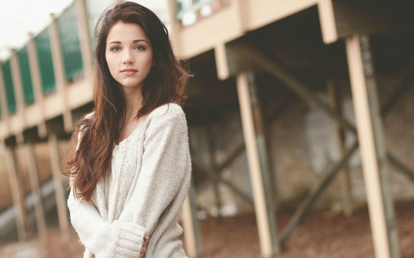 Une femme en pull blanc et jeans se tenant devant un bâtiment (emily rudd, modèle, beauté, mannequin, épaule)