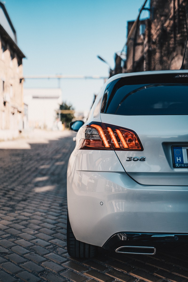 Крупный план белого автомобиля, припаркованного на кирпичной дороге (пежо, peugeot, машина, автомобильное освещение, семейный автомобиль)