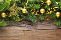 Festliche Weihnachtsdekorationen mit goldenen Ornamenten und immergrünen Zweigen auf rustikalem Holz.