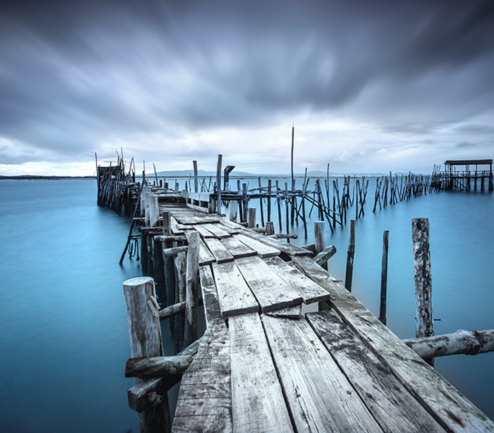 Arafed wooden pier with a cloudy sky and water (antique, dock, landscape)