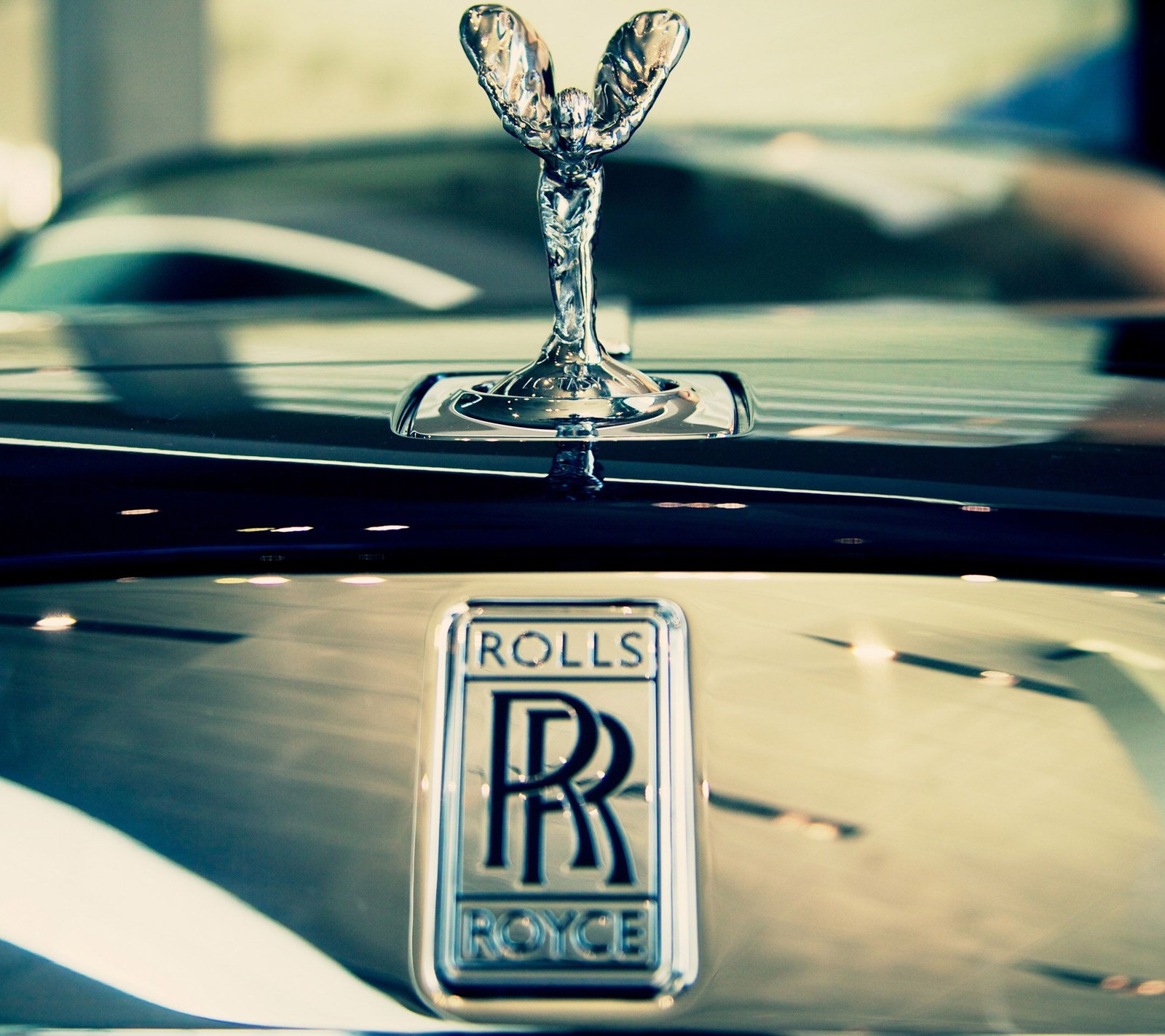 A close up of a car hood ornament with a logo on it (cars, luxury, rolls royce)