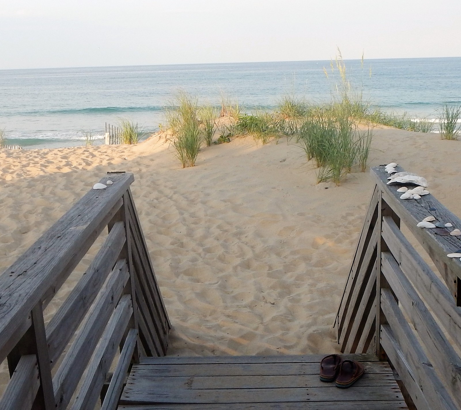 Una escalera de madera que conduce a la playa con un par de zapatos sobre ella (playa, naturaleza)