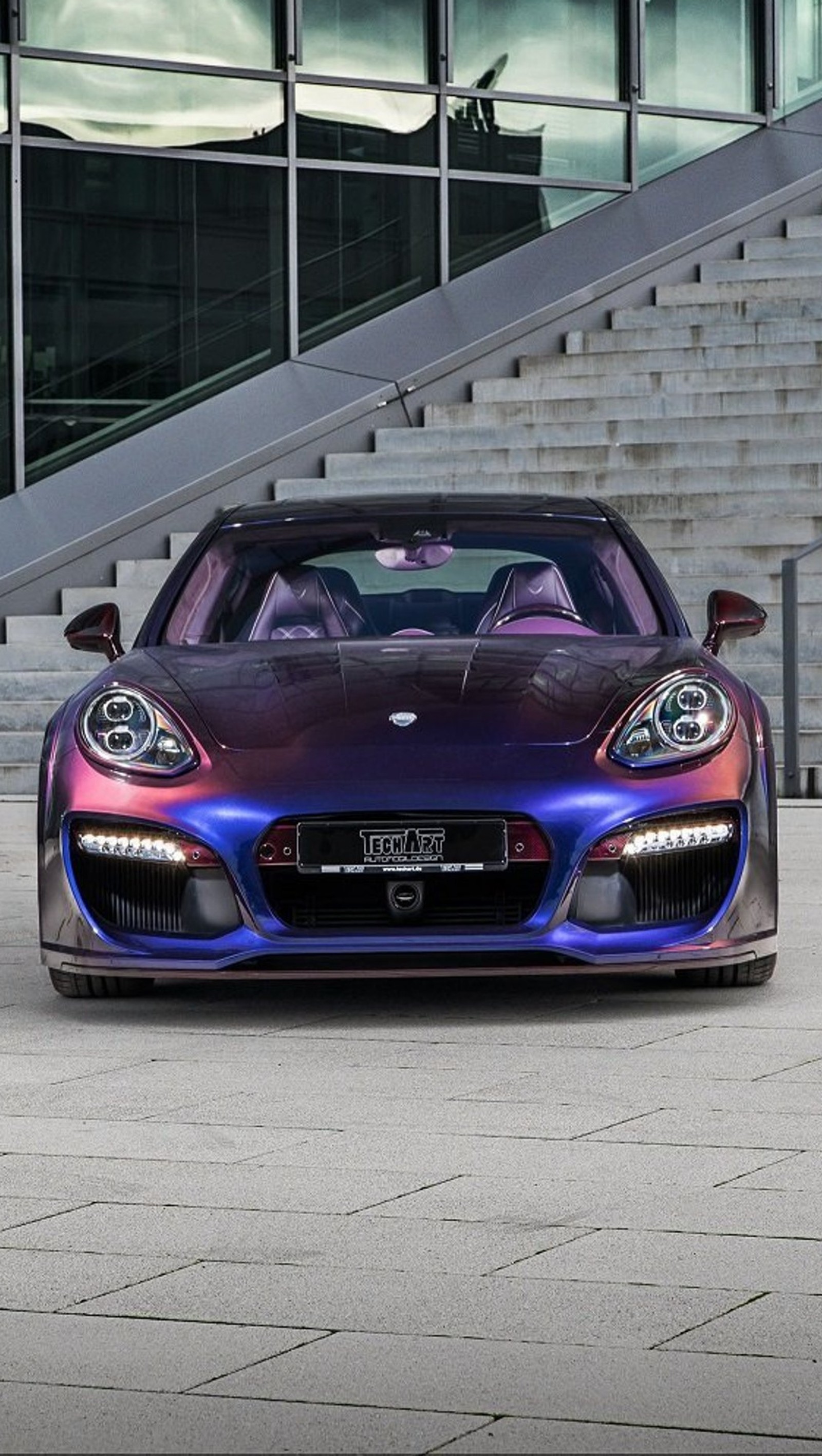 Un primer plano de un coche deportivo morado estacionado frente a un edificio (coche, modificado, panamera, porsche)