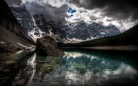 Lago Moraine: Un reflejo sereno del Valle de los Diez Picos en medio de cielos dramáticos.