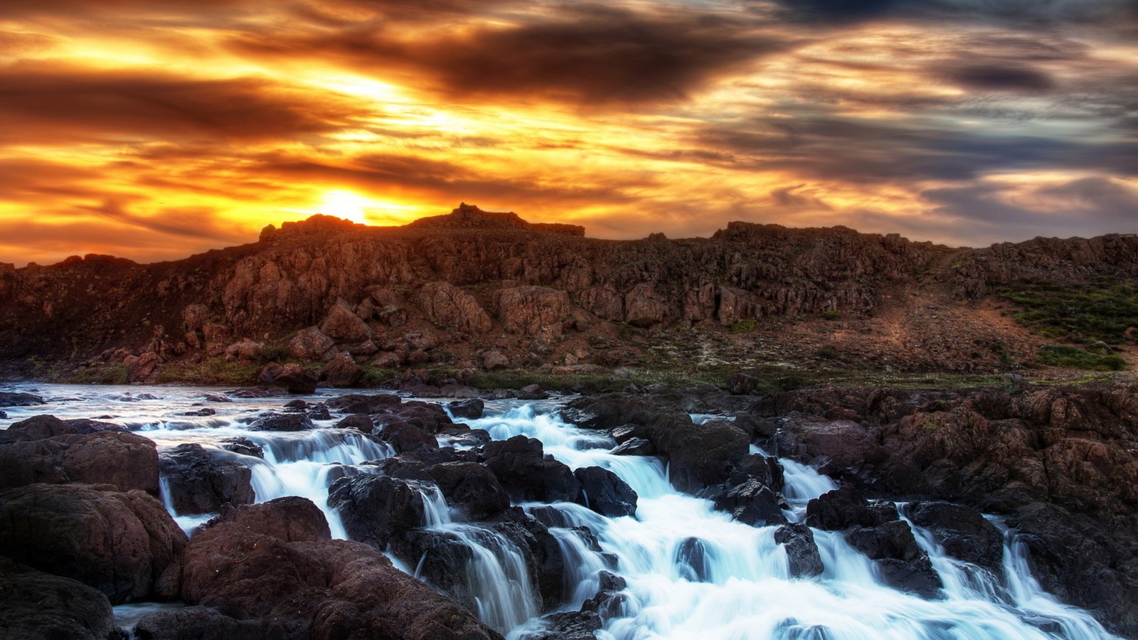 A beautiful sunset over a waterfall in the middle of a rocky area (sunset, nature, water, rock, cloud)