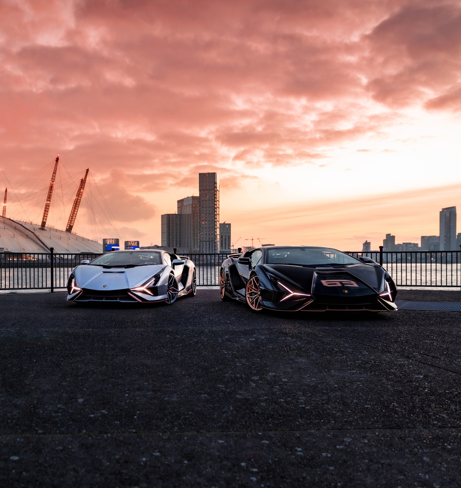 Dos coches deportivos estacionados en un estacionamiento con una ciudad de fondo (lamborghini sián fkp 37, hipercoches, 2021, 5k, coches)