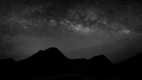 Paisaje nocturno en monocromo con cielo estrellado y siluetas de montañas