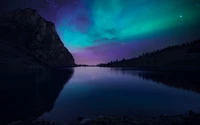 Majestätische Aurora Borealis über dem Bannalpsee: Eine ruhige Nachtlandschaft mit Bergsilhouetten und reflektierenden Gewässern