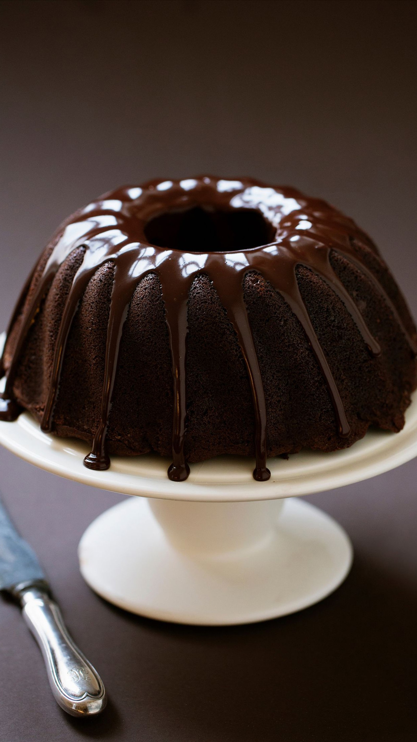 Hay un pastel de chocolate en un soporte para pasteles blanco (tcl, pudin de chocolate, chocolate, espejo, comida)