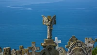 Estátua de anjo com vista para o mar em um cemitério costeiro