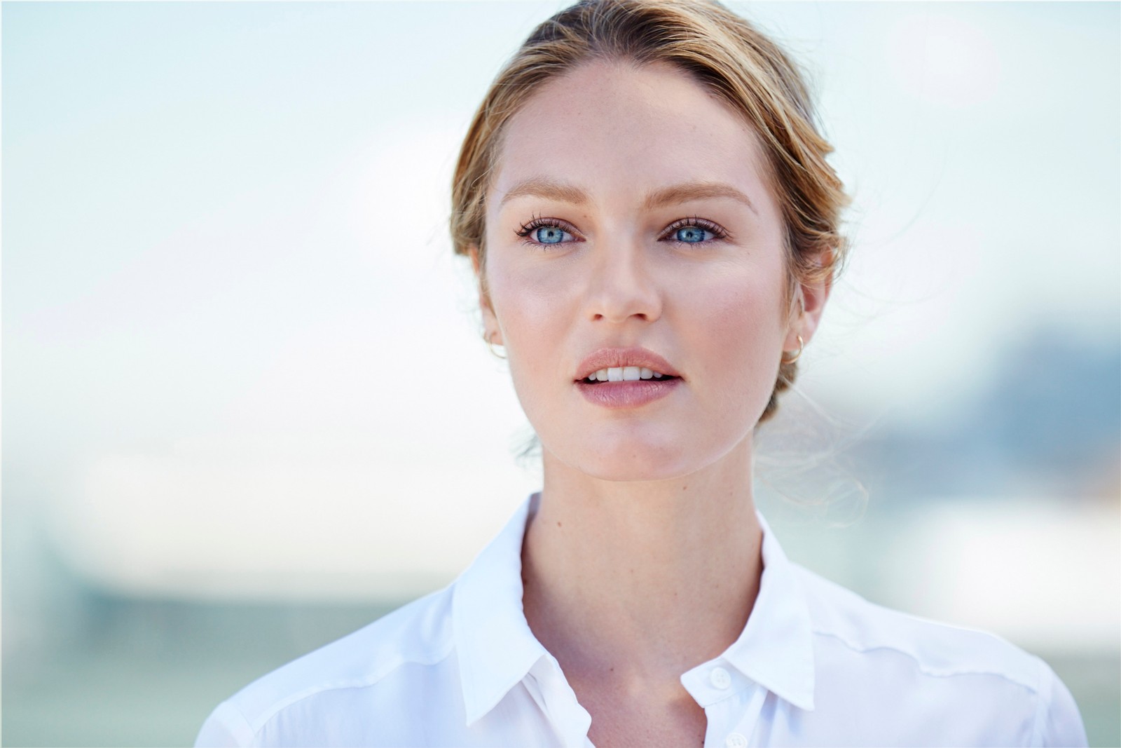 Une femme blonde aux yeux bleus et à la chemise blanche regarde l'appareil photo (candice swanepoel, modèle, victorias secret, visage, peau)