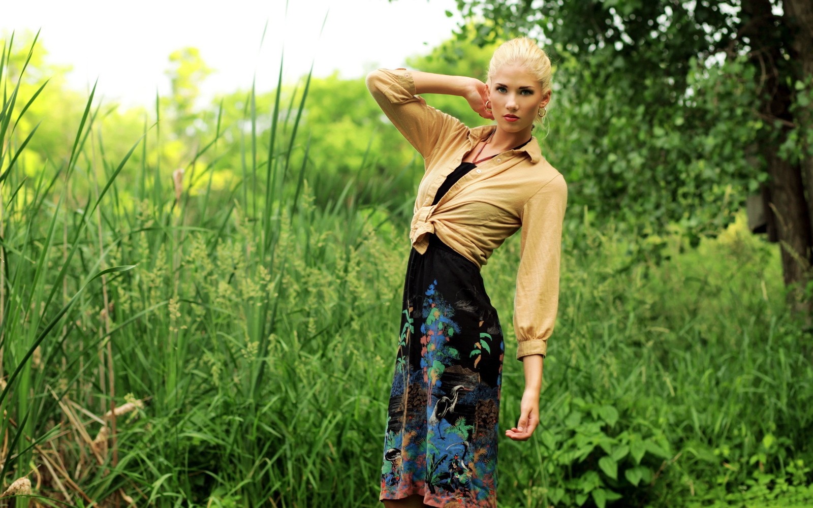 Mulher loira em uma saia floral e camiseta amarela posando em um campo (verão, pradaria, agricultura, planta, menina)