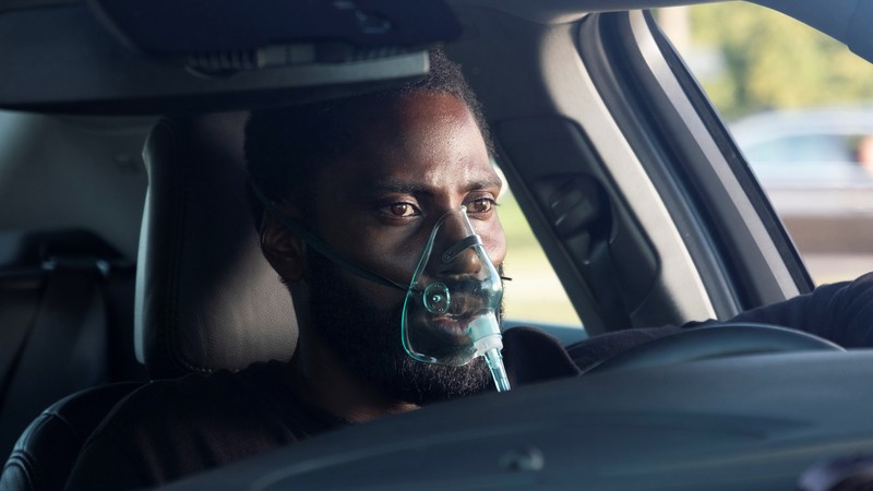 Un árabe en un coche con una máscara de respiración (tenet, 2020, película, john david washington)