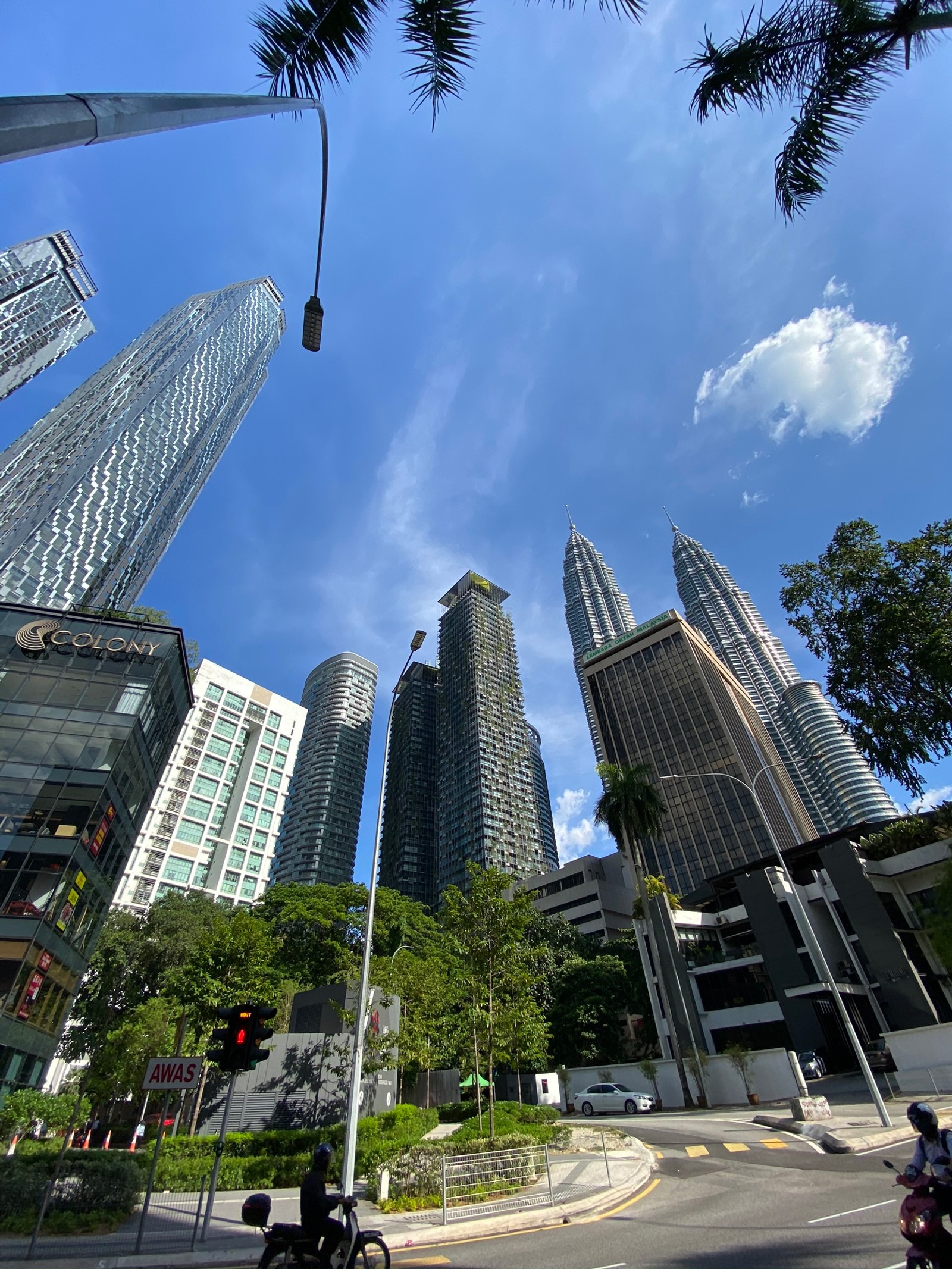 Prédios altos em uma cidade com algumas pessoas em uma motocicleta (bloco de torre, torre, arranha céus, prédio comercial, edifício)