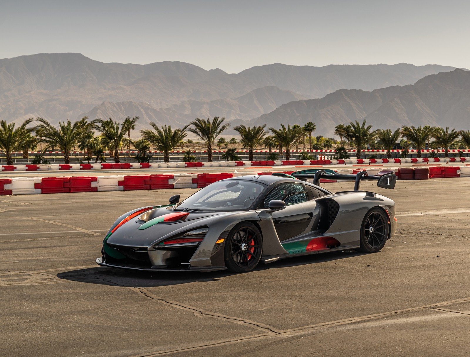 Un primer plano de un coche en una pista con montañas de fondo (mclaren senna xp el triunfo absoluto, hipercoches, 2022, 5k, coches)