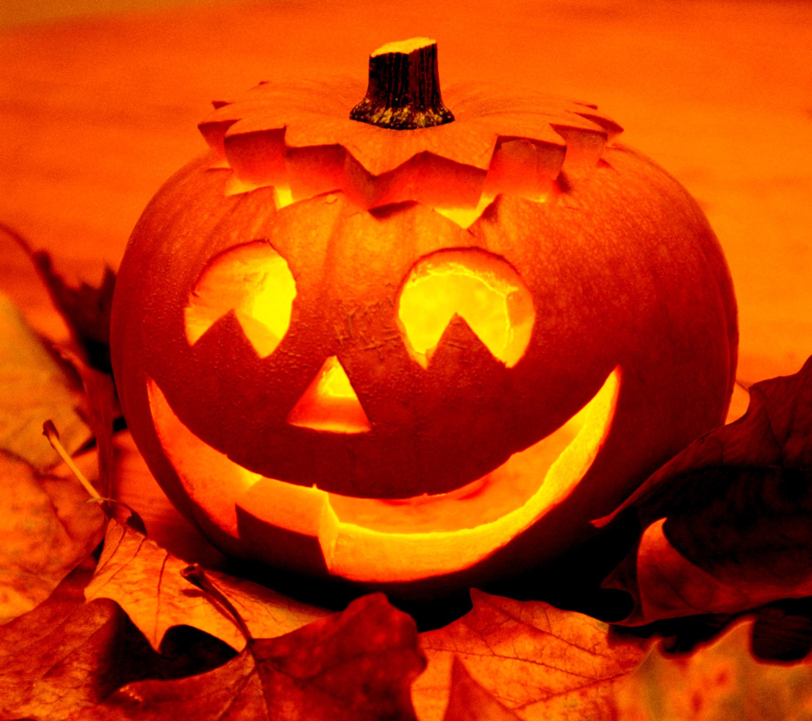 Une citrouille avec des visages sculptés et des feuilles sur une table (halloween, vacances, horreur, octobre)