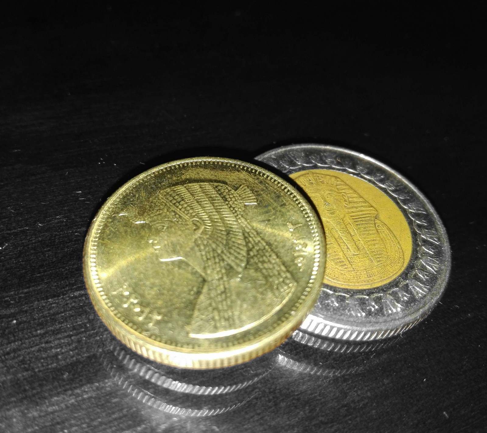 Dos monedas se encuentran una encima de la otra sobre una mesa (moneda, egipto, oro, dinero)