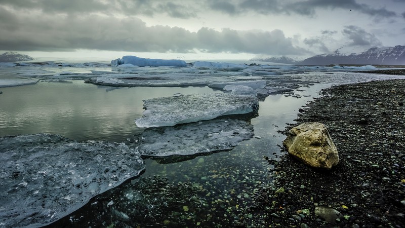 Большая скала лежит на пляже рядом с водоемом (водоем, вода, море, побережье, океан)