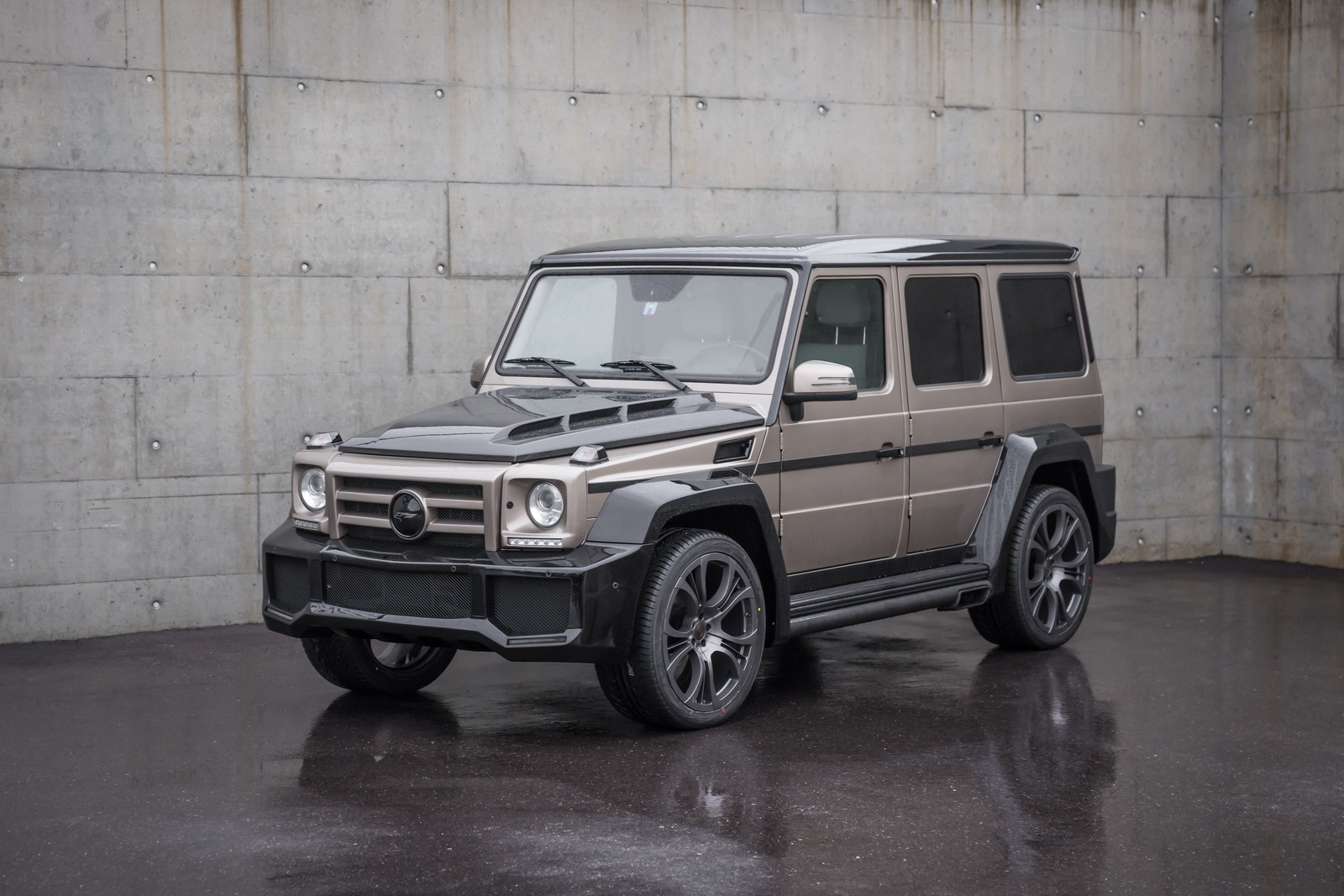 Un véhicule armé garé dans un parking avec un mur en arrière-plan (voiture, pneu automobile, mercedes benz g class, roue, jante)