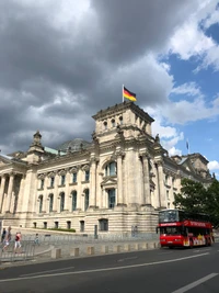 Bâtiment du Reichstag à Berlin avec un bus touristique sous des nuages dramatiques