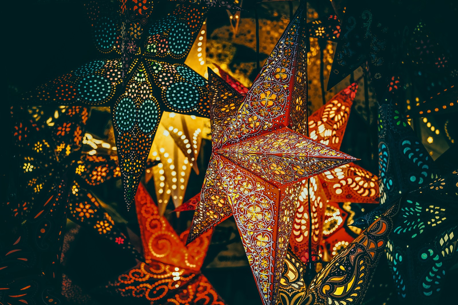 Estrelas de papel iluminadas penduradas no teto de uma sala escura (luzes de natal, estrelas, enfeite de natal, fundo escuro, bonito)